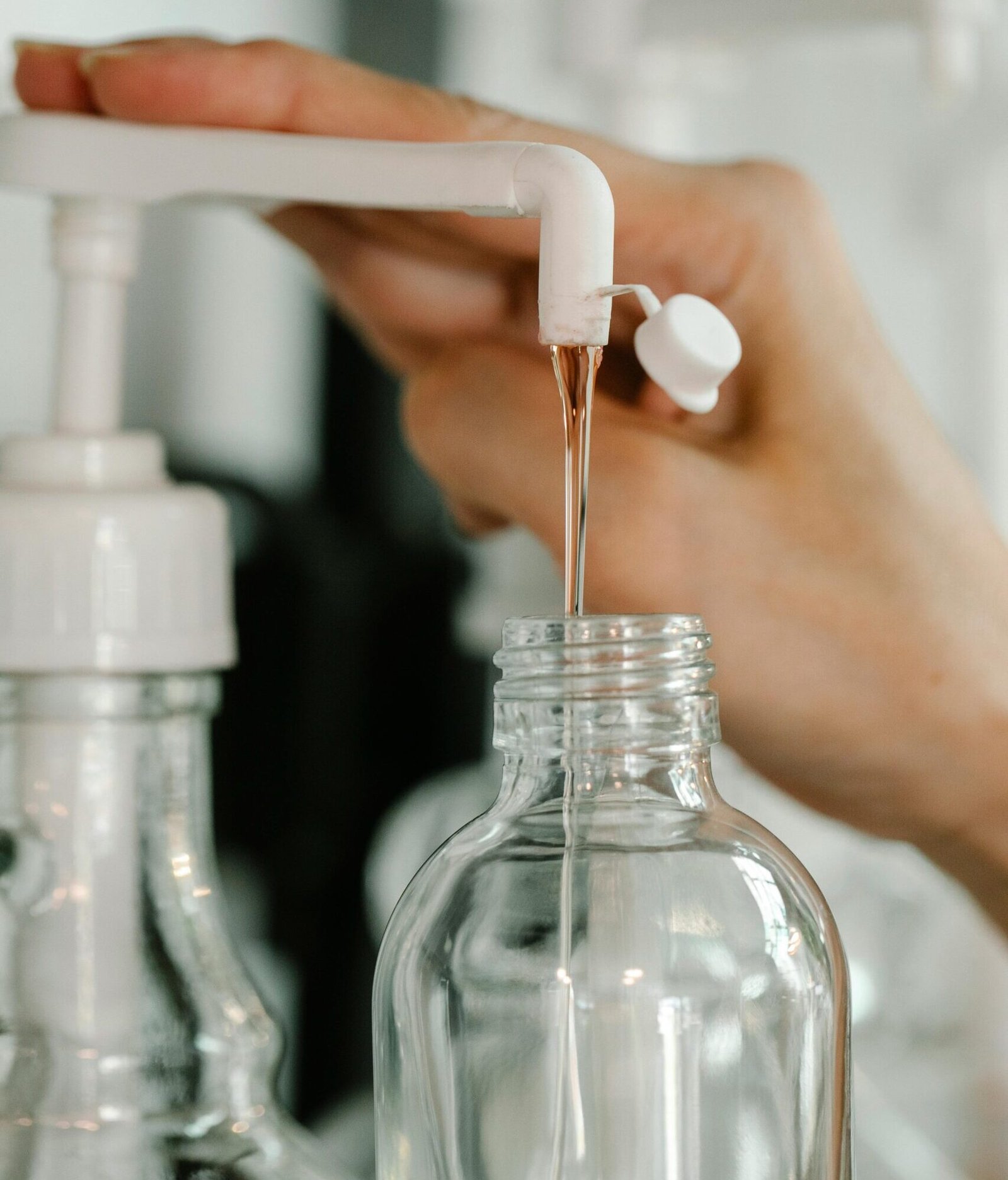 A close-up shot of liquid being poured from a dispenser into a bottle, emphasizing cleanliness and hygiene.